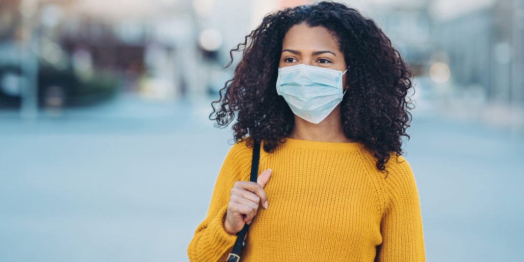 Young woman walking outdoors with a face mask
