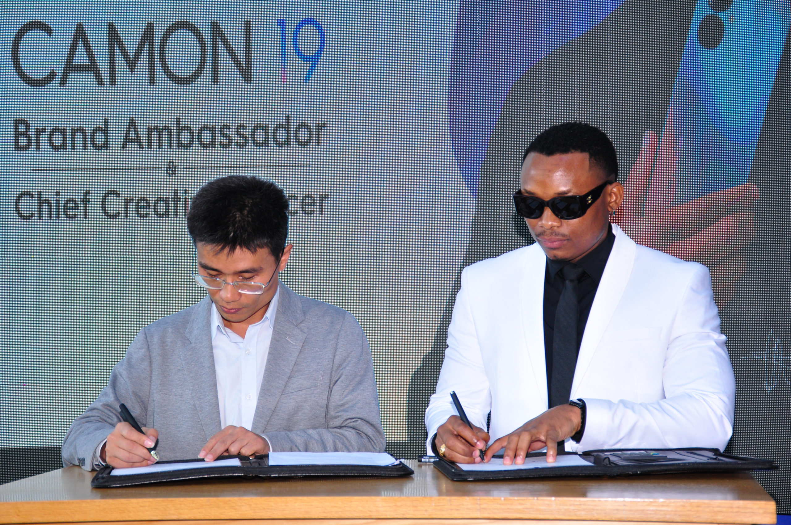 From Right Otile Brown and TECNO Mobile Kenya Brand Manager Peter Shi sign partnership to unveil him as the Chief Creative Officer for CAMON 19 Series scaled
